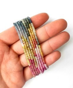 Strands of gorgeous multi-colored sapphire beads wrapped around a woman's hand.
